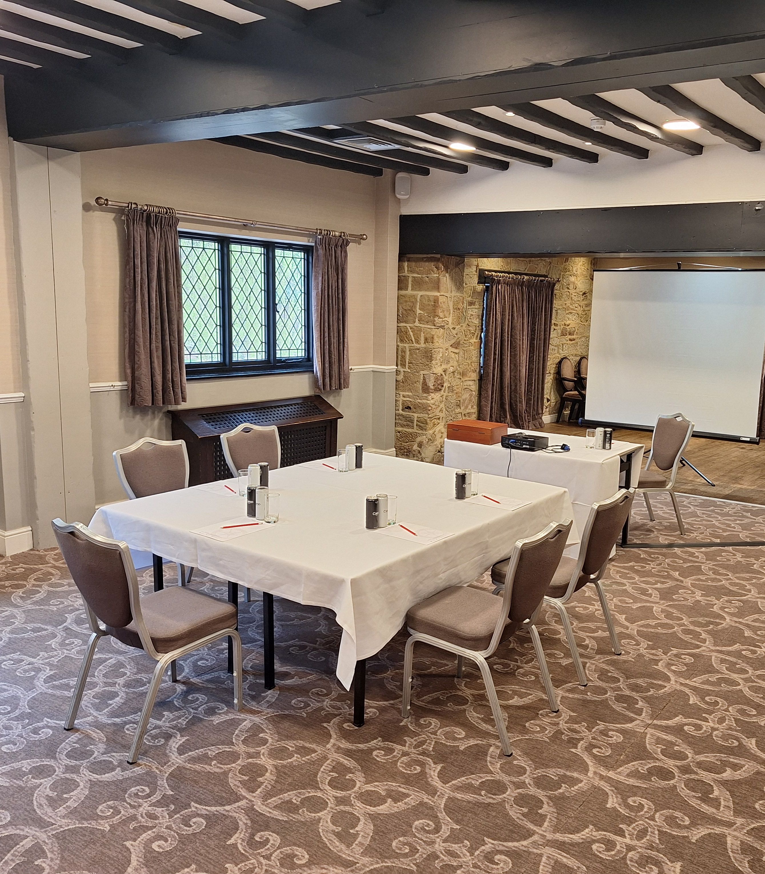 A conference room with a table, chairs, and a projector screen.