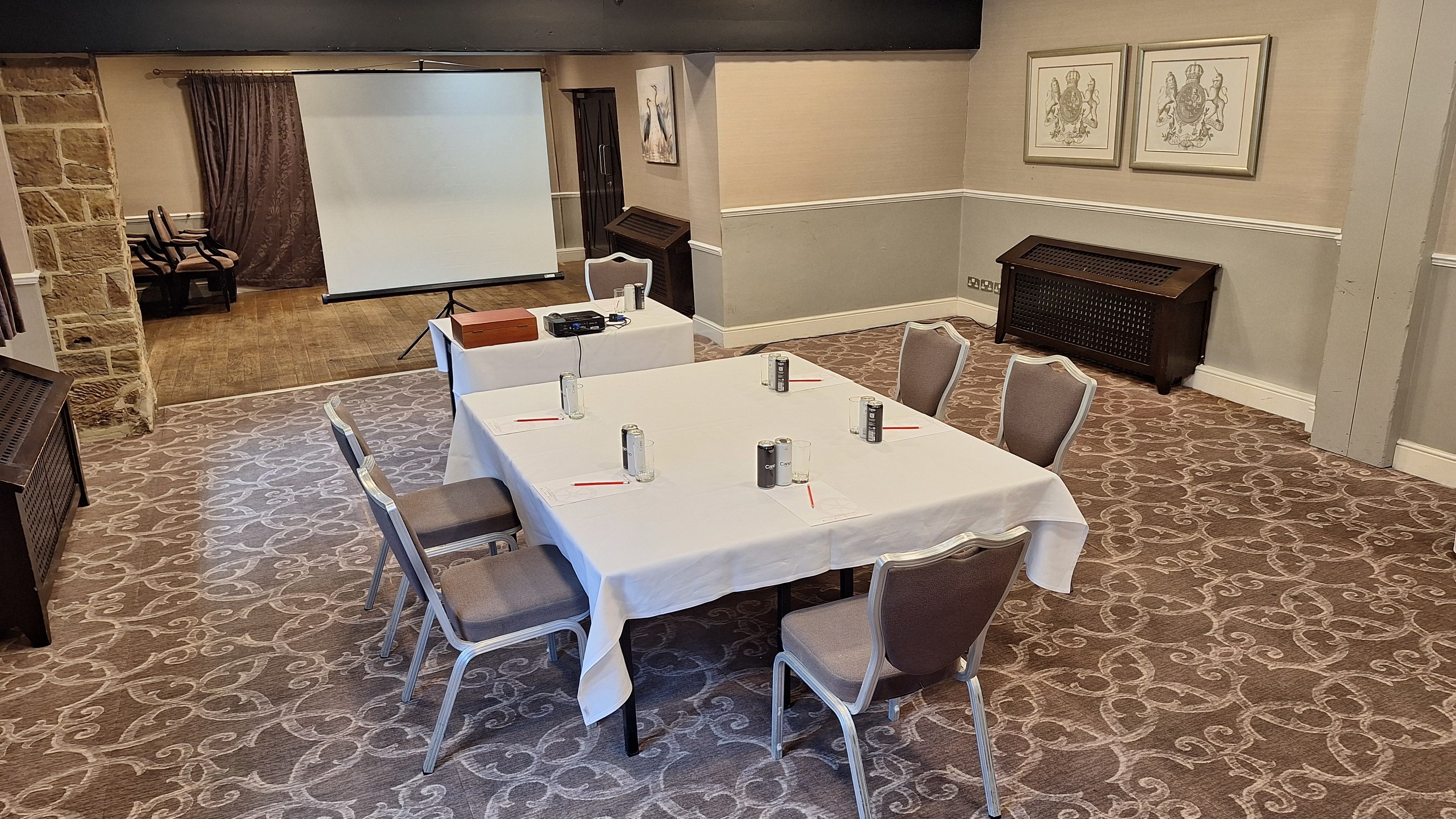 Conference room with a rectangular table, six chairs, projector, screen, and notepads.
