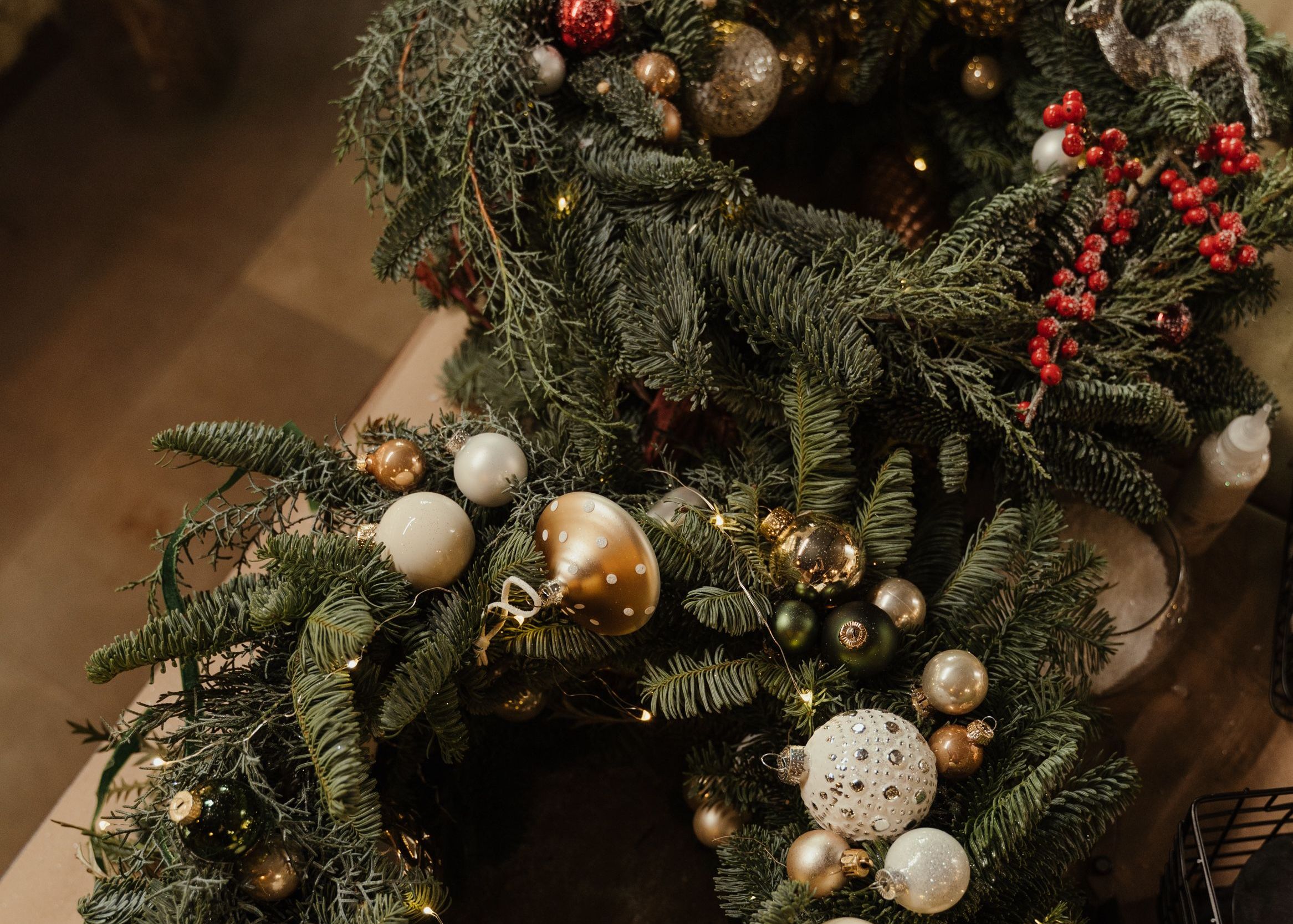 Decorated Christmas wreaths with ornaments and berries on a table
