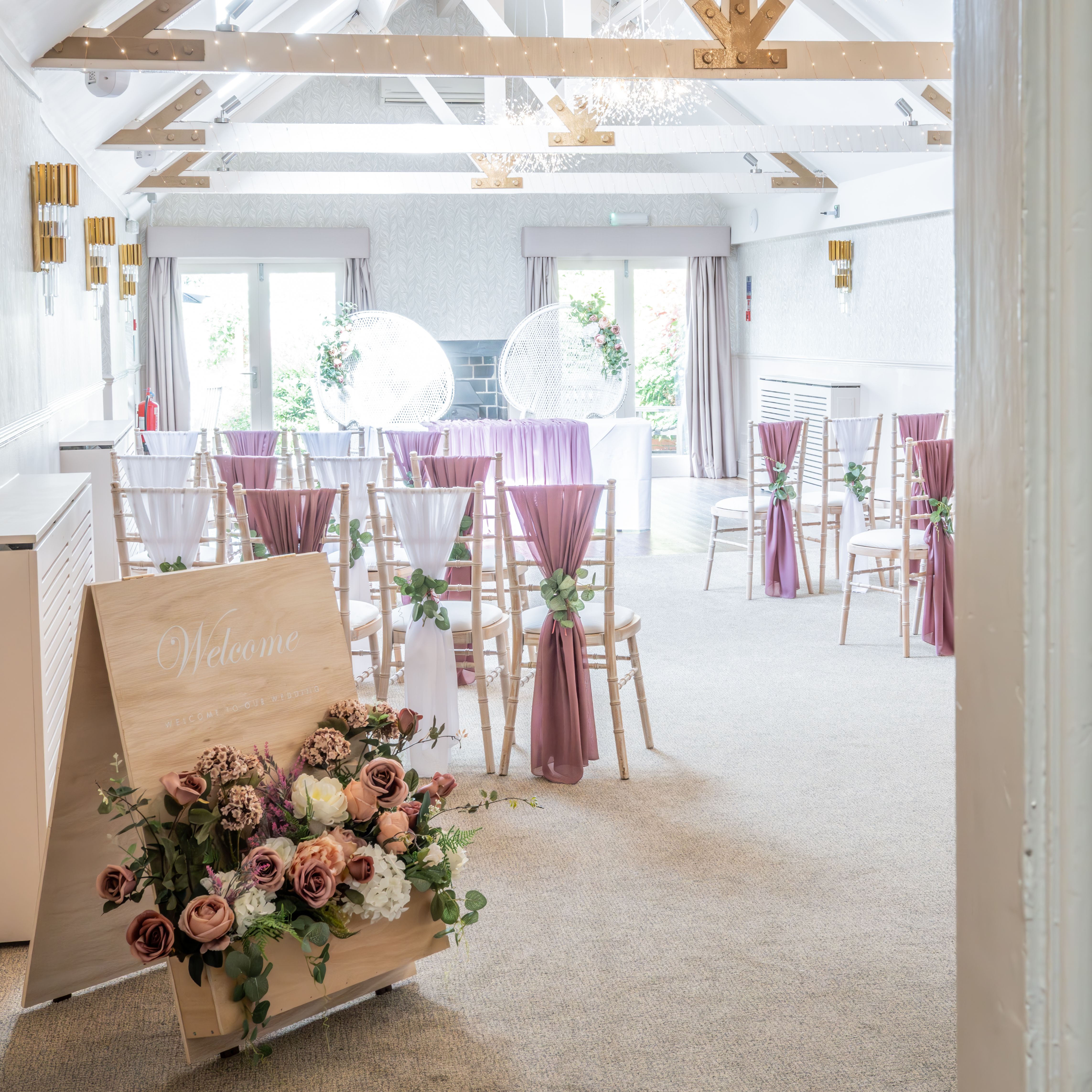 Elegant indoor wedding ceremony setup with flower arrangements and draped chairs