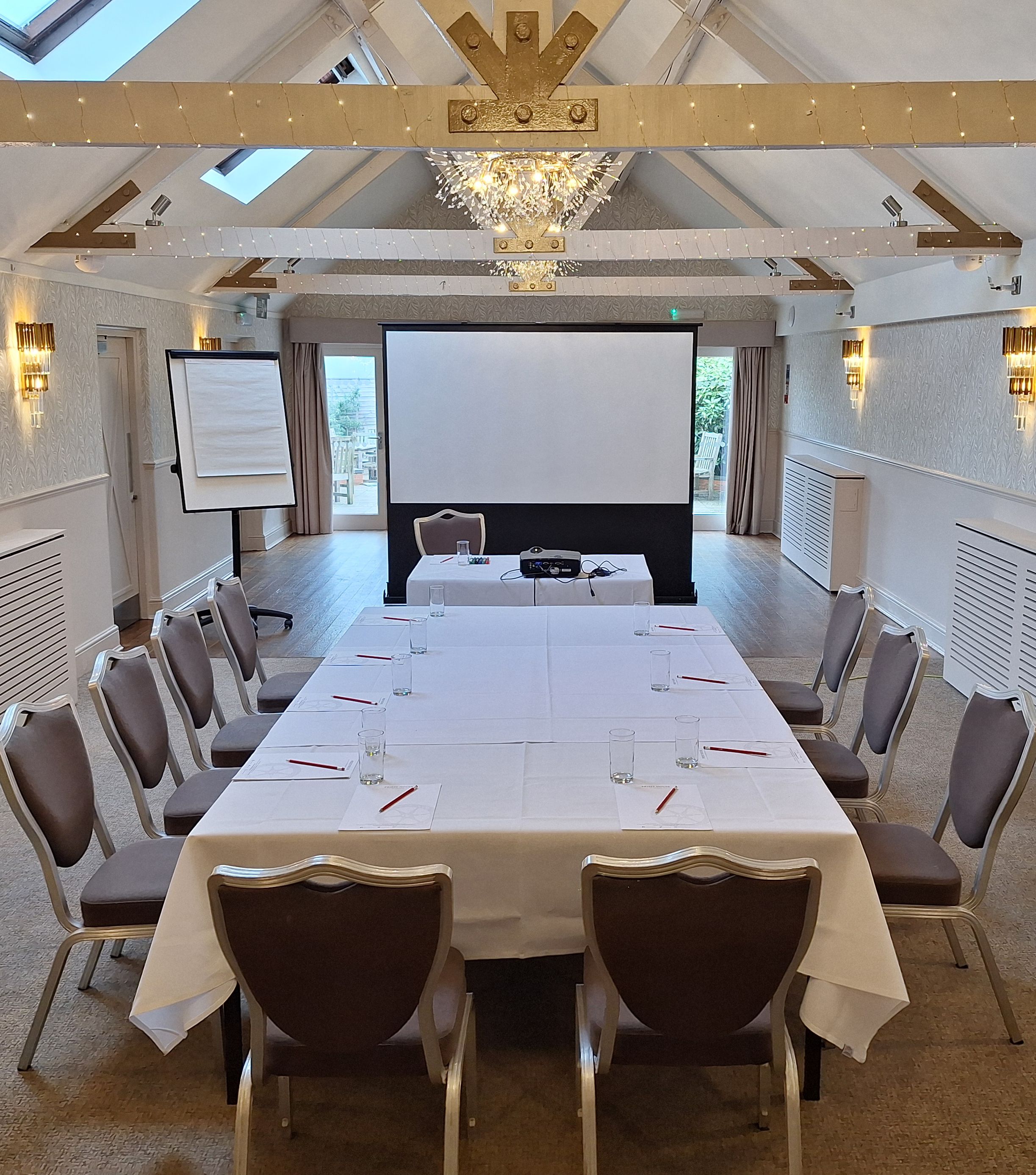 Modern conference room with a U-shaped table, chairs, projector screen, and flip chart