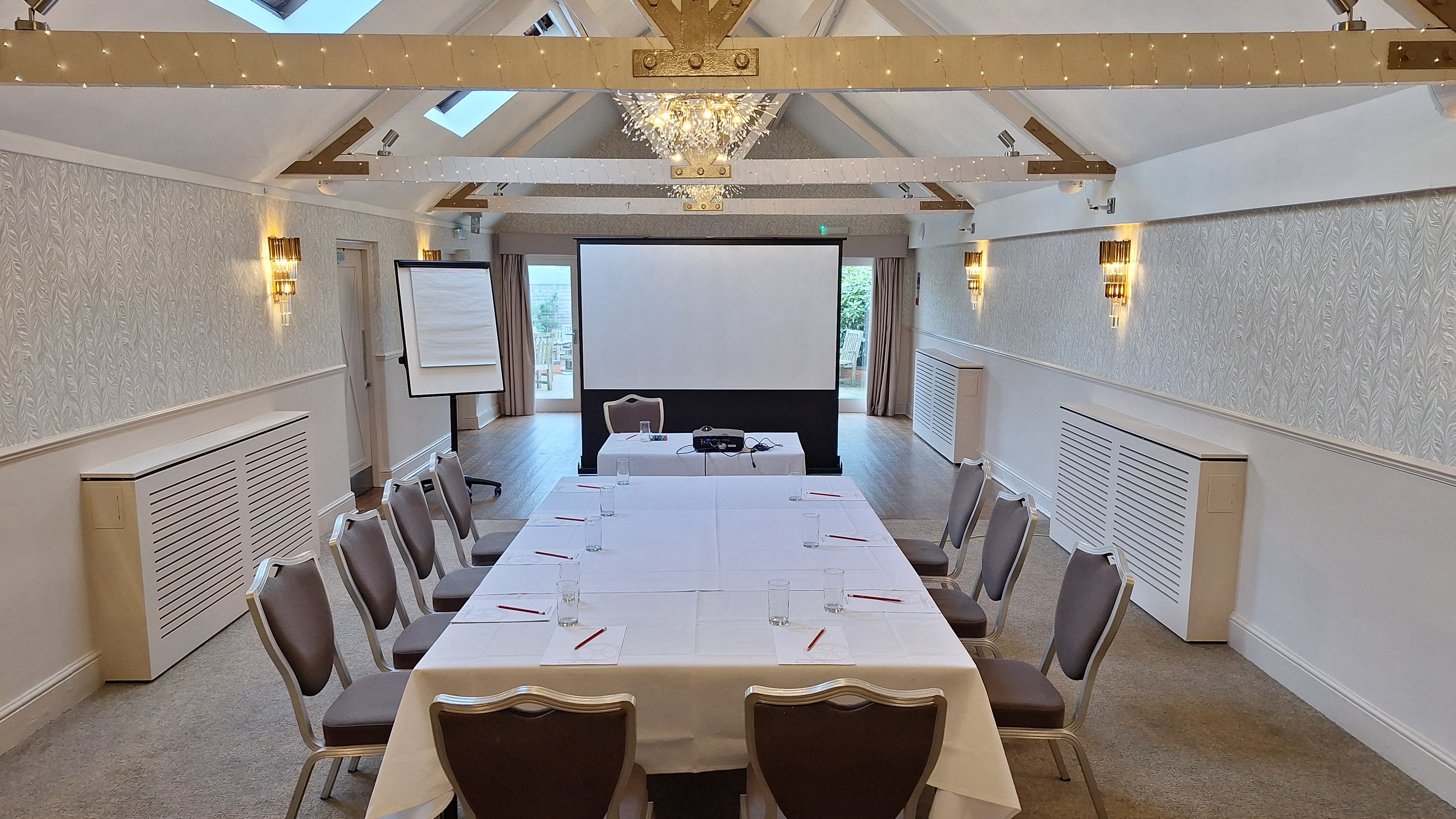 Modern conference room with a U-shaped table, chairs, projector screen, and flip chart