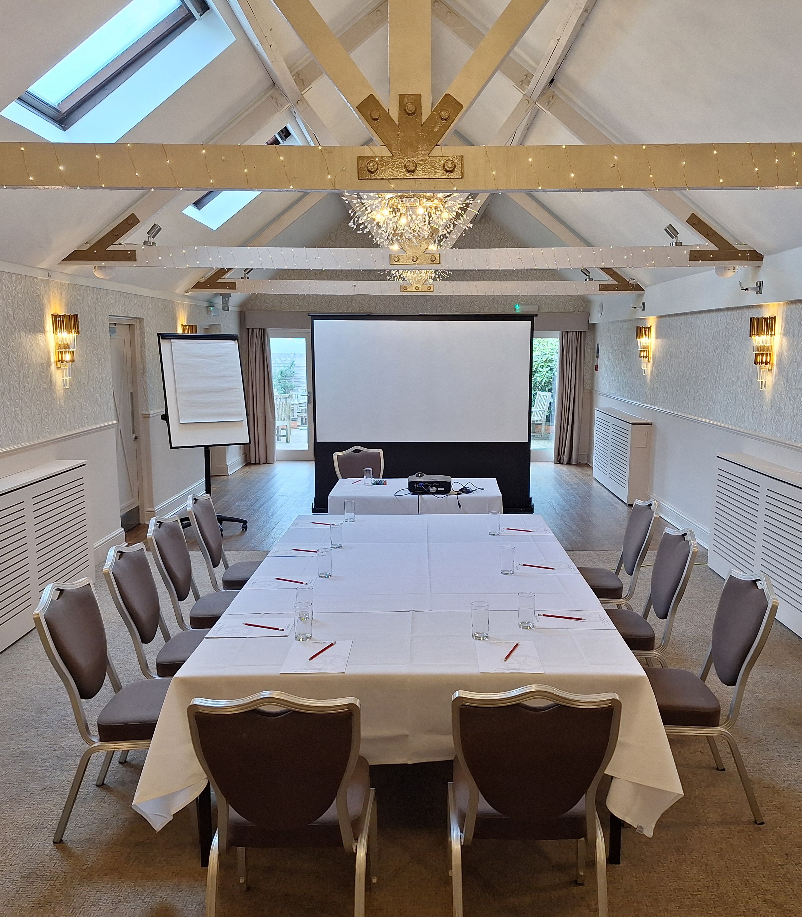 Modern conference room with a U-shaped table, chairs, projector screen, and flip chart