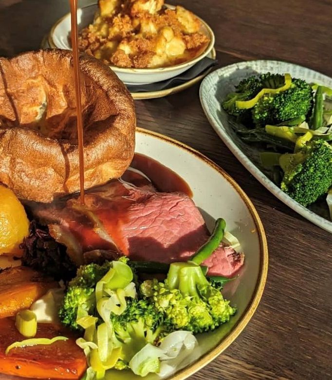 Traditional British Sunday roast with Yorkshire pudding, roast beef, roast potatoes, carrots, broccoli, and gravy