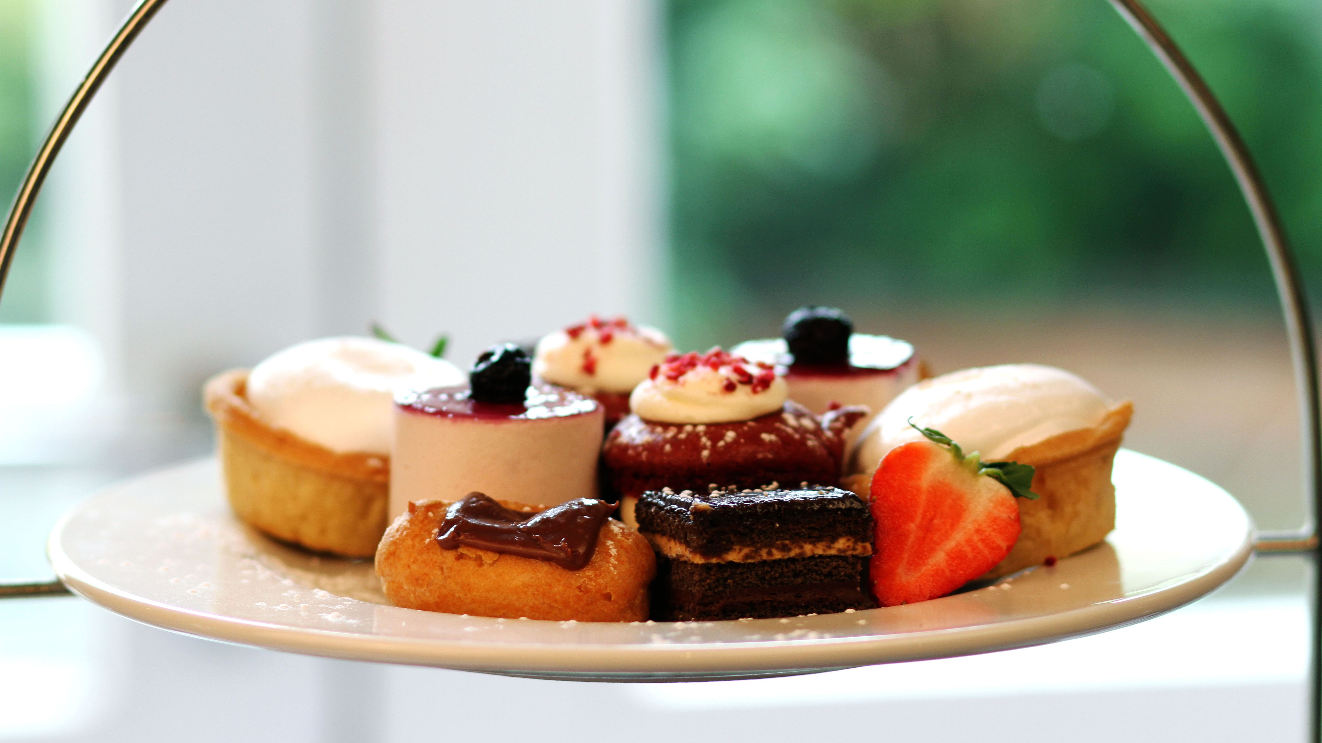 A plate of assorted mini desserts including pastries, cakes, and a sliced strawberry