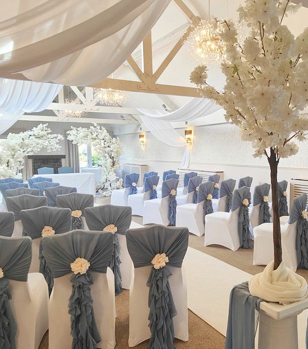 Elegant wedding ceremony setup with white floral decorations and blue chair sashes