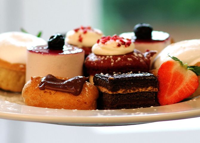 A plate of assorted mini desserts including cakes, pastries, and a strawberry.
