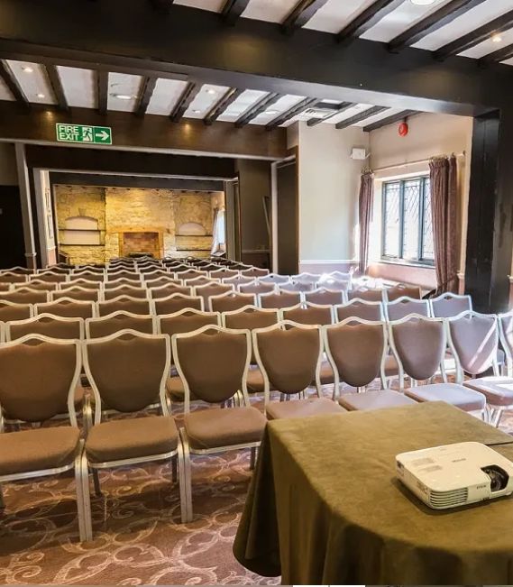 Conference room with rows of chairs, a projector on a table, and a fireplace at the front