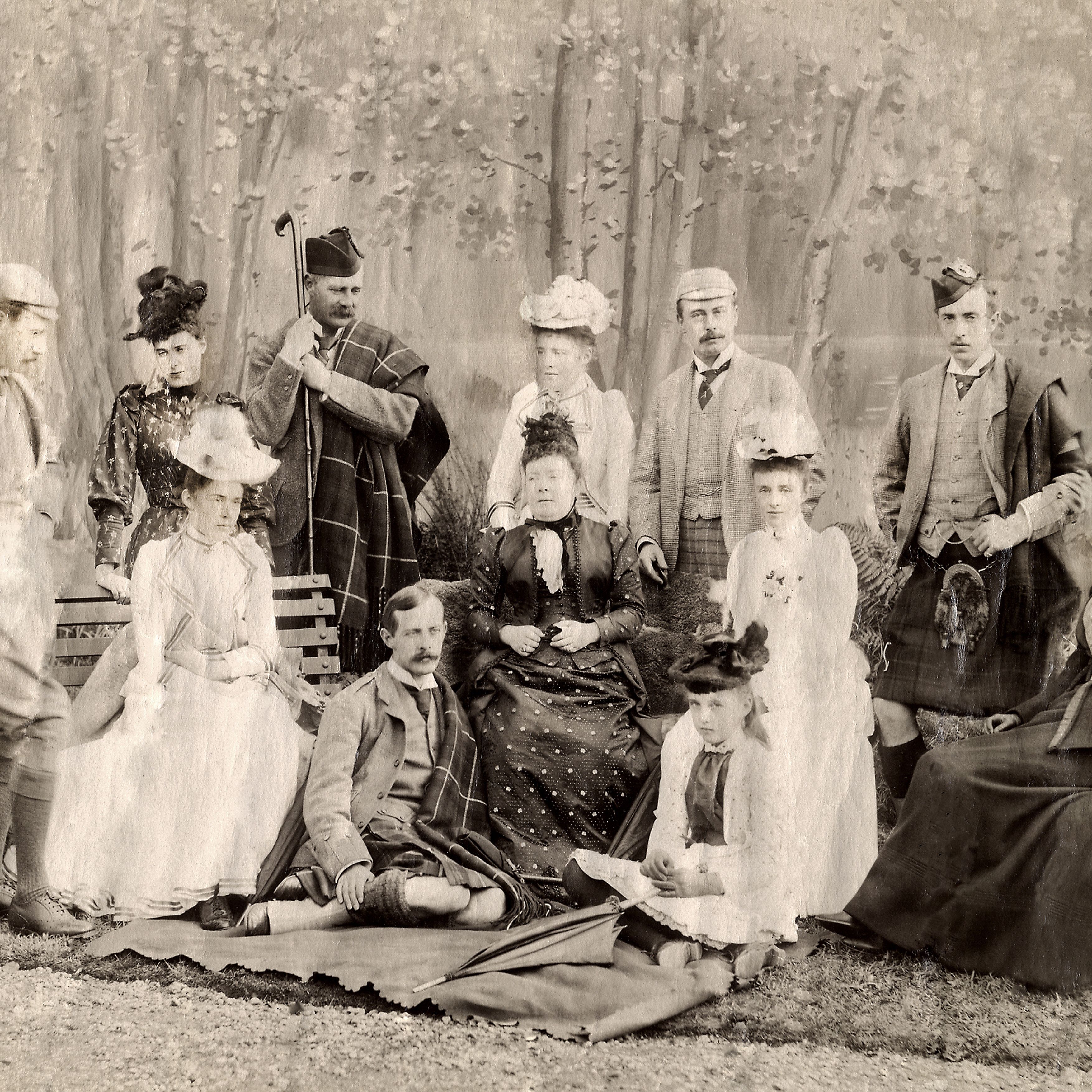 Victorian era group portrait with men and women outdoors, many in period formal dress and hats