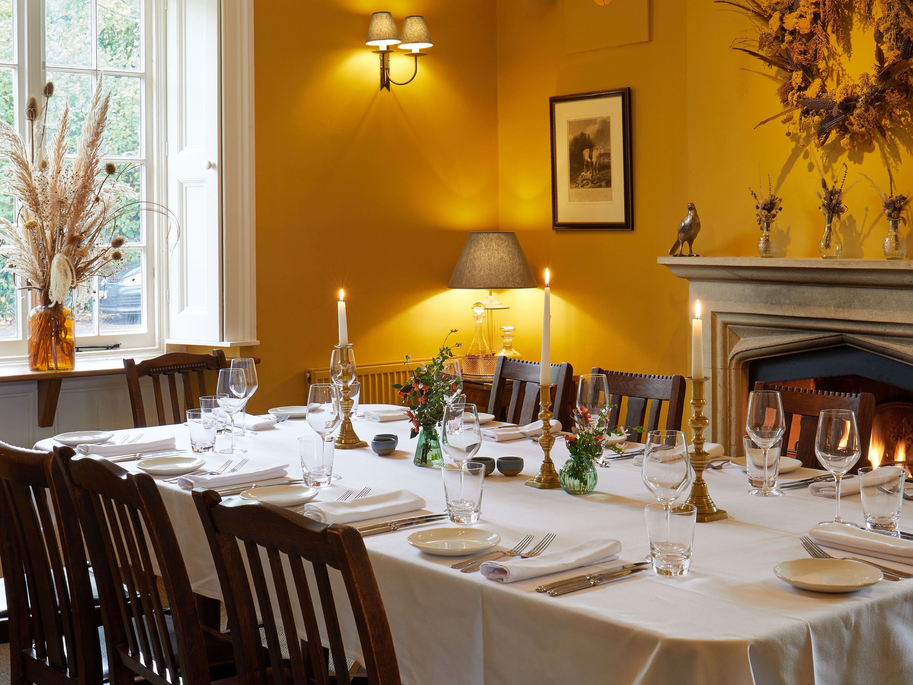 Elegant dining room with a set table, lit candles, and yellow walls.