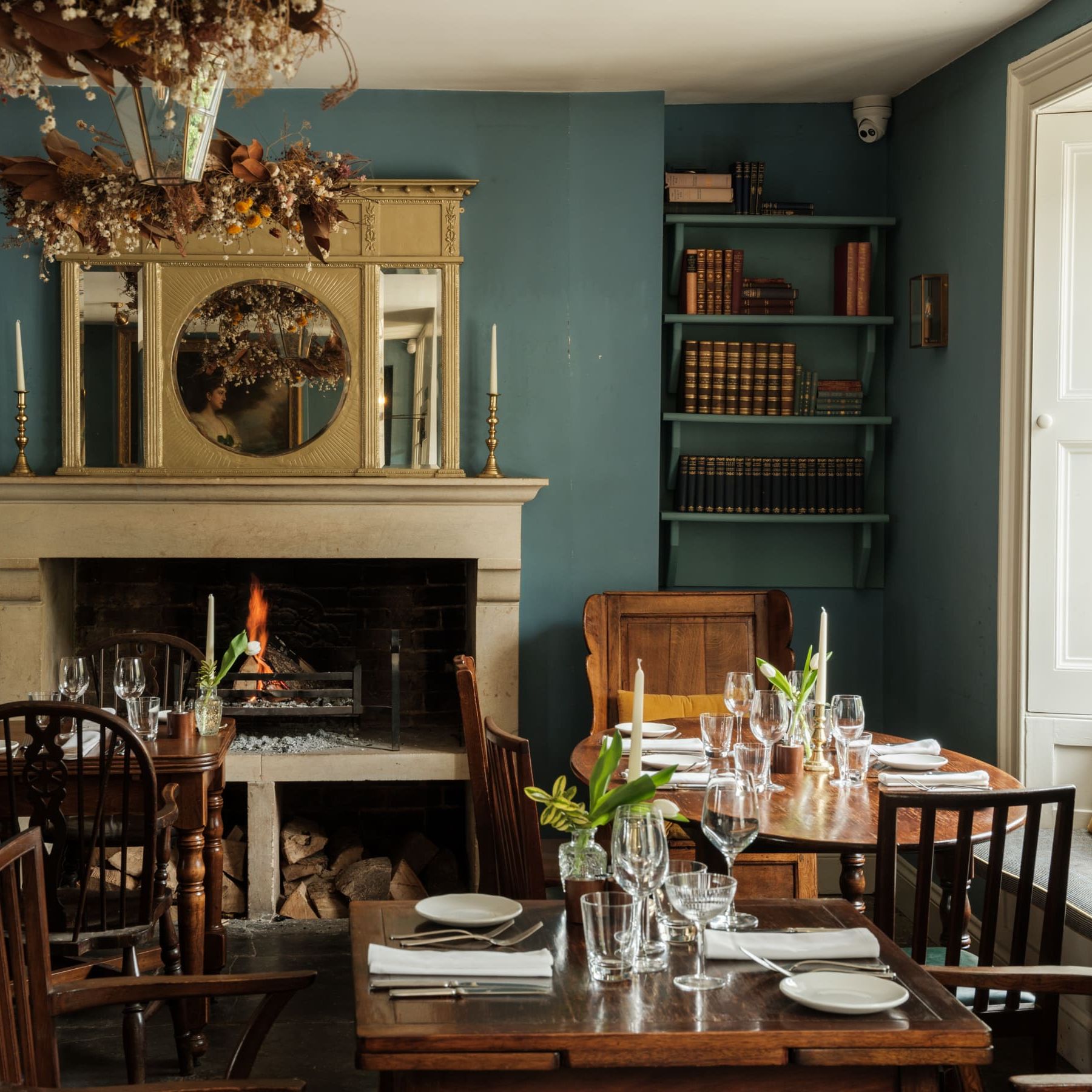 Cozy restaurant dining area with a lit fireplace, wooden tables, and elegant place settings.