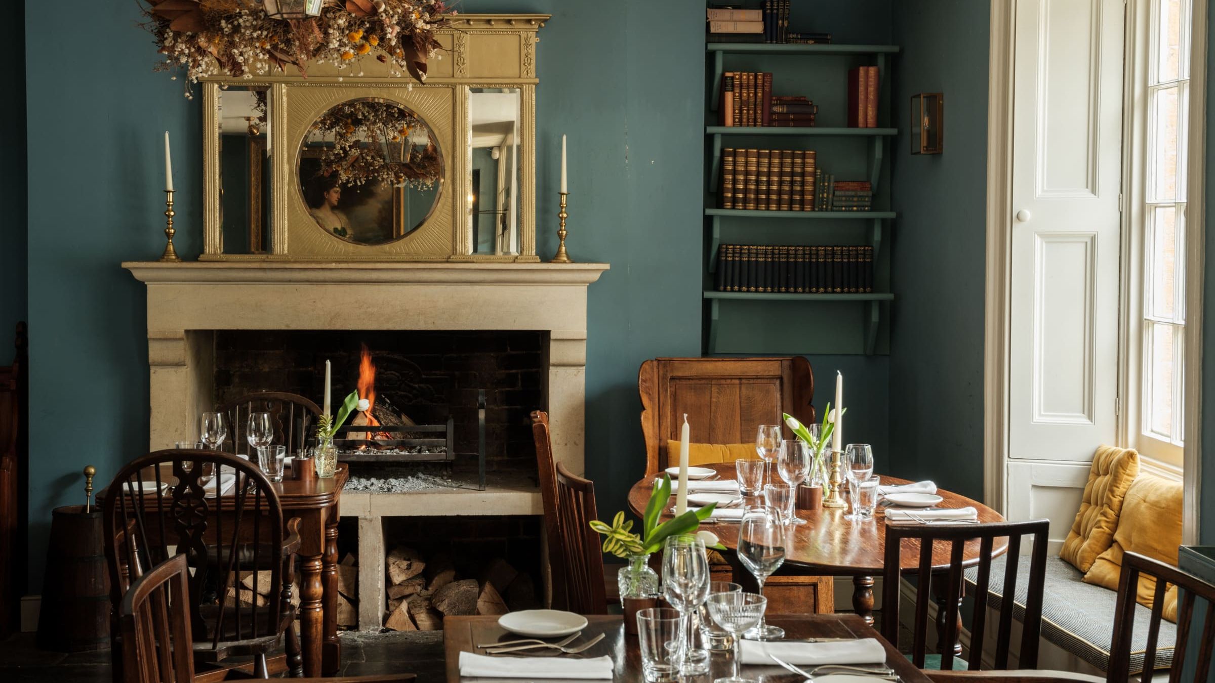 Cozy restaurant dining area with a lit fireplace, wooden tables, and elegant place settings.