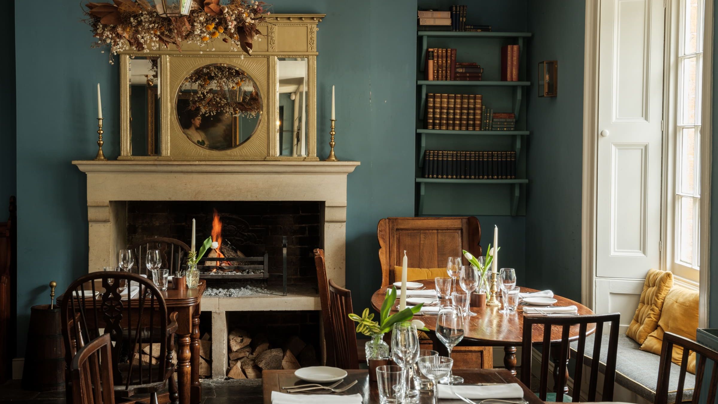 Cozy restaurant dining area with a lit fireplace, wooden tables, and elegant place settings.