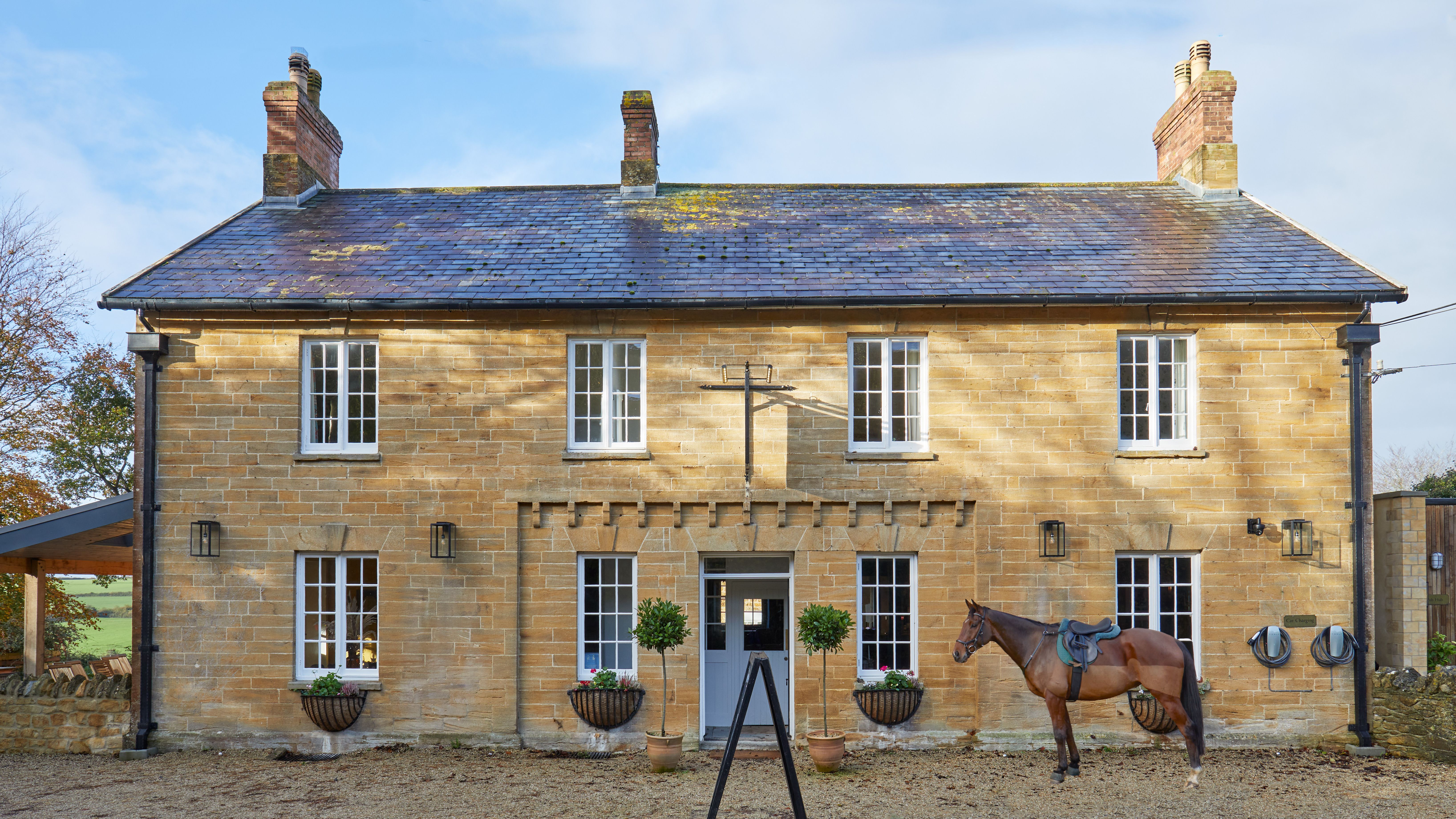 Traditional stone country house with a horse standing in front