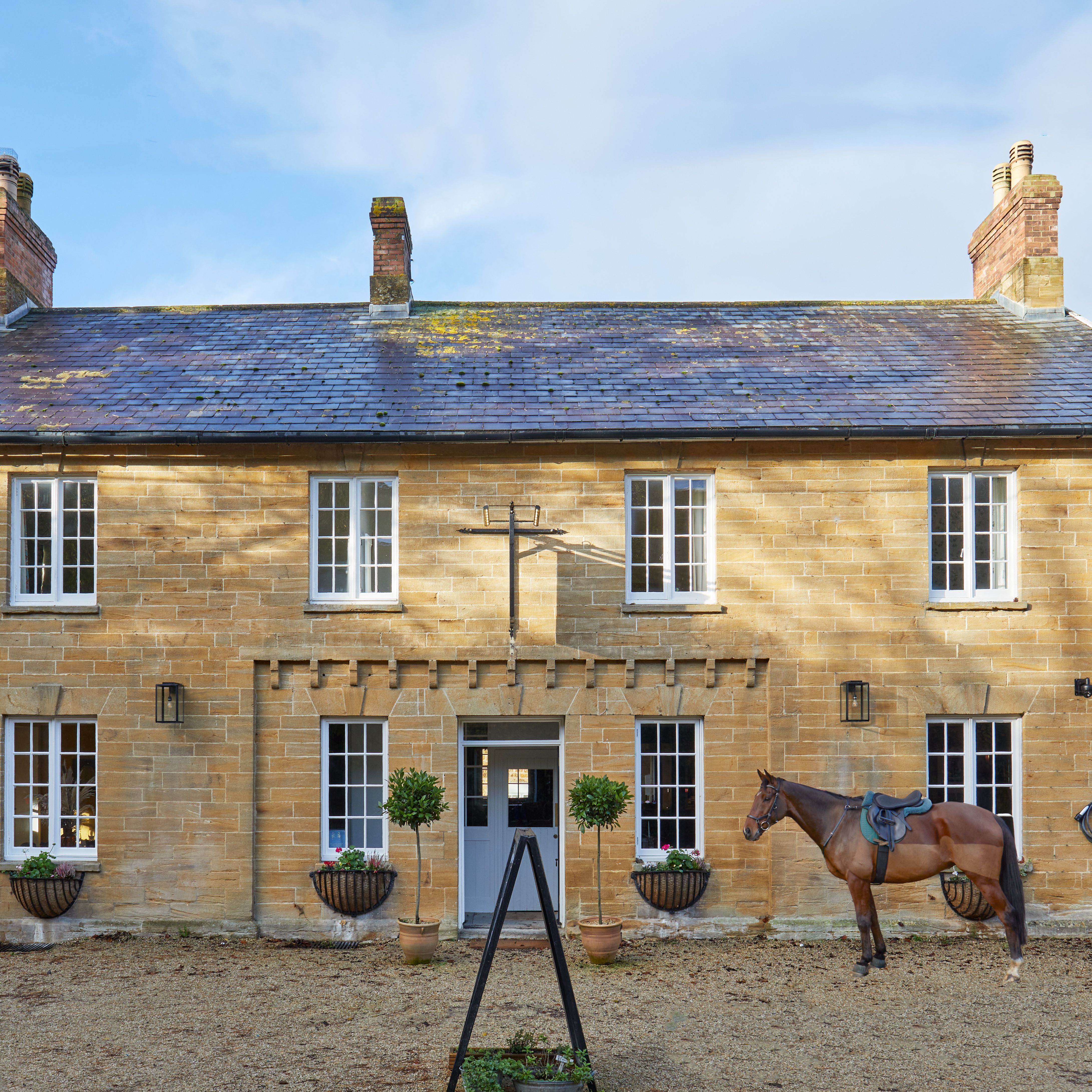 Traditional stone country house with a horse standing in front