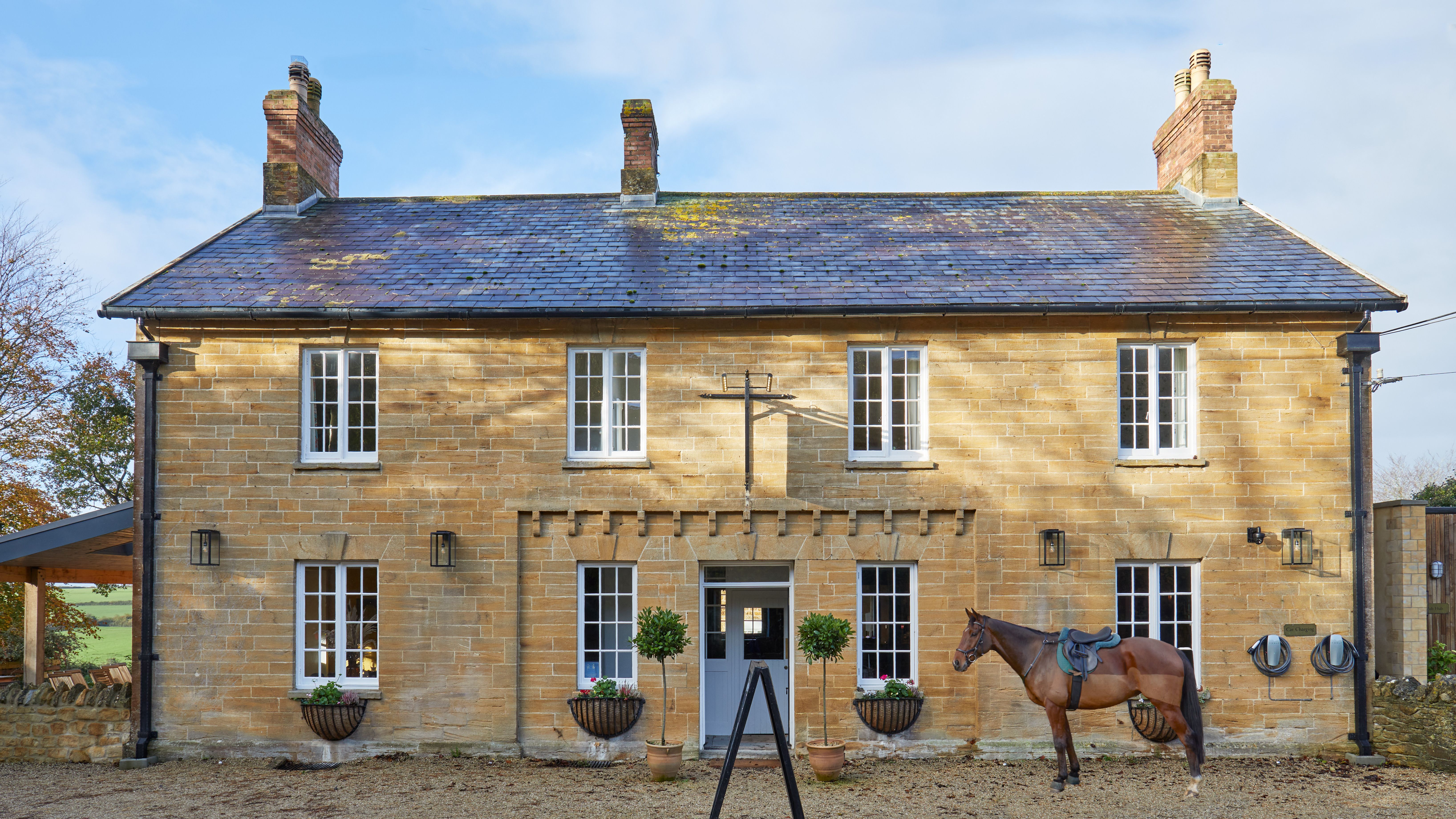Traditional stone country house with a horse standing in front
