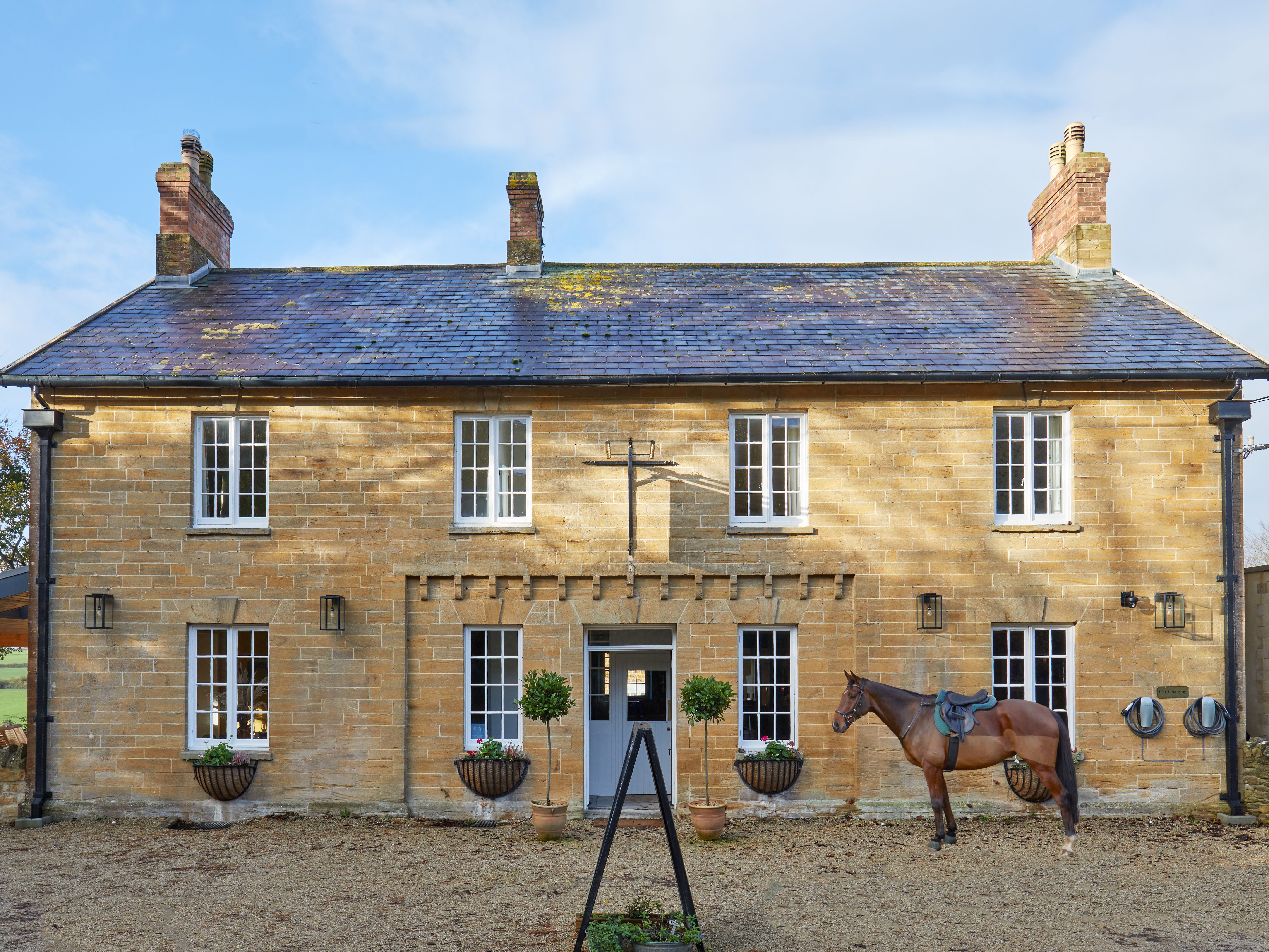 Traditional stone country house with a horse standing in front
