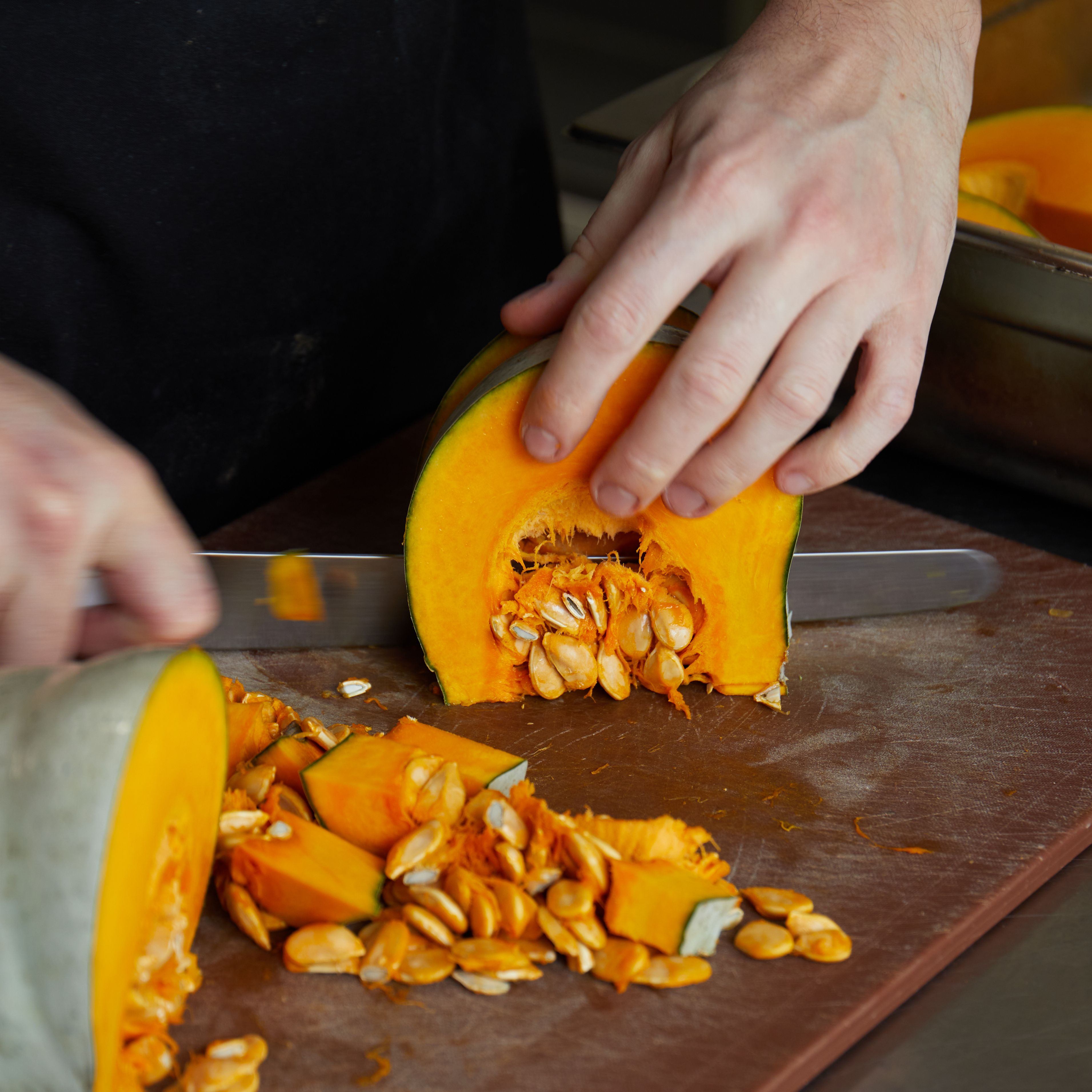 Person cutting a pumpkin on a chopping board with a knife