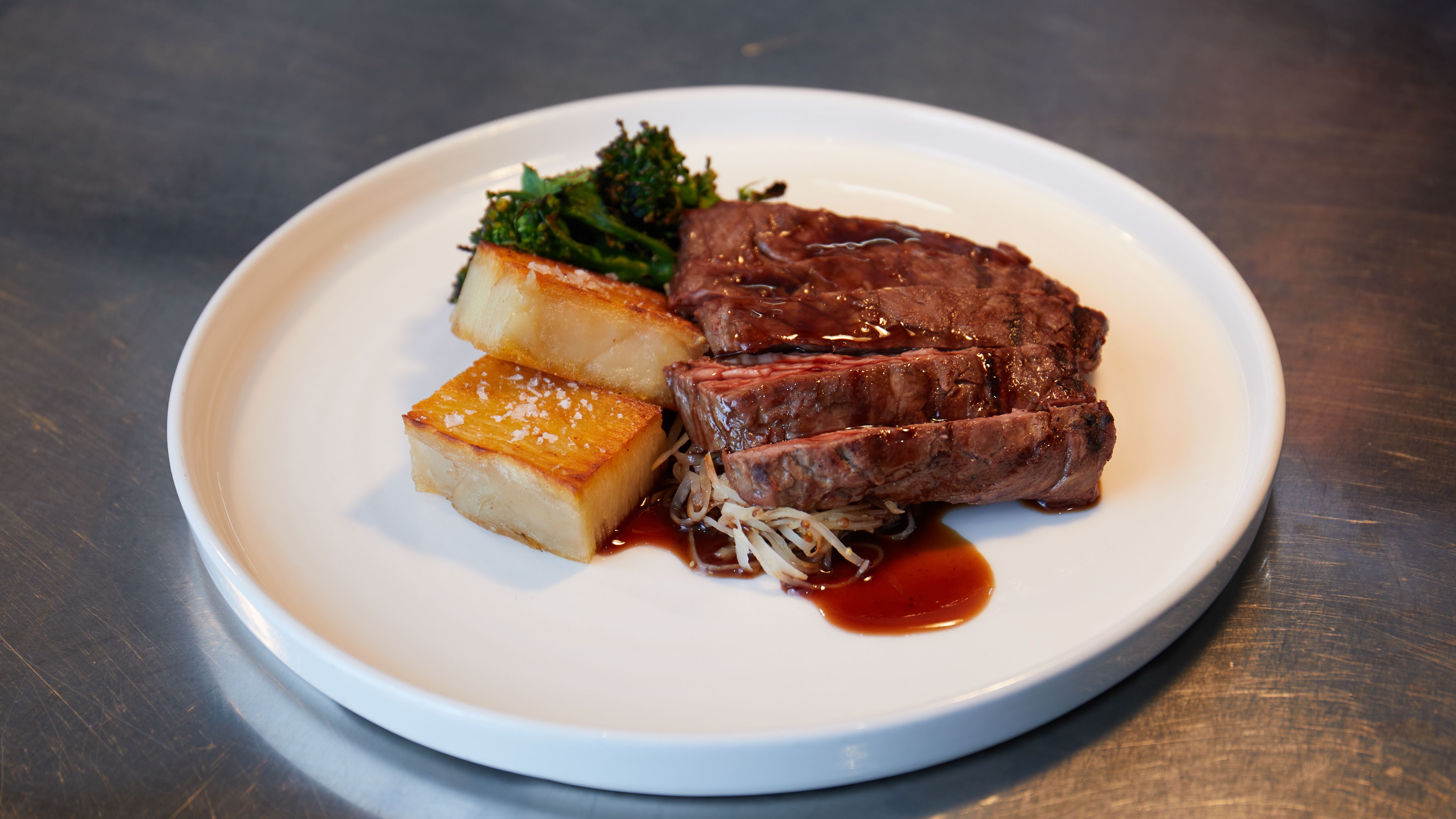 Plate with steak, roasted potatoes, broccolini, and sauce