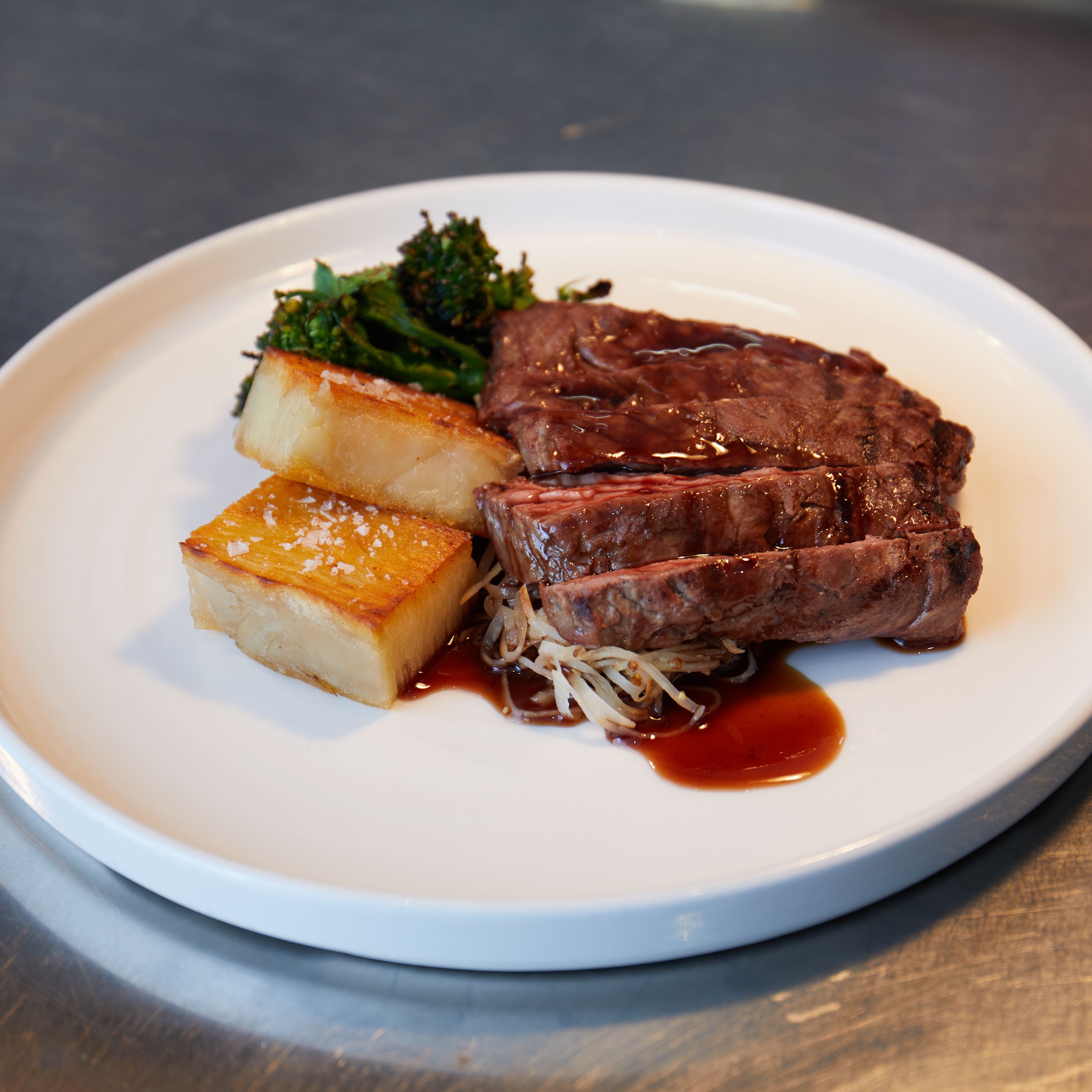 Plate with steak, roasted potatoes, broccolini, and sauce