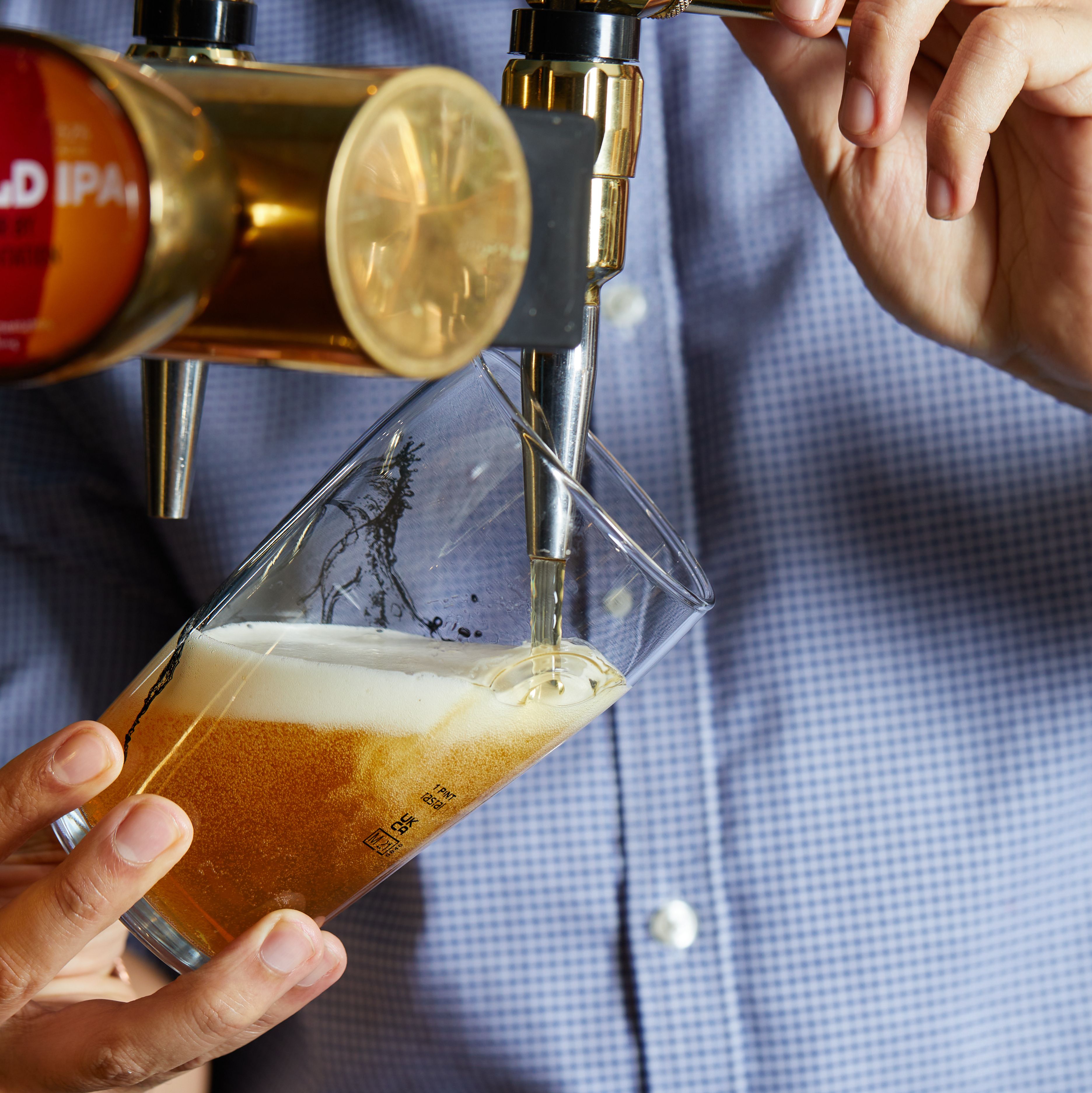 Person pouring a pint of beer from a tap into a glass