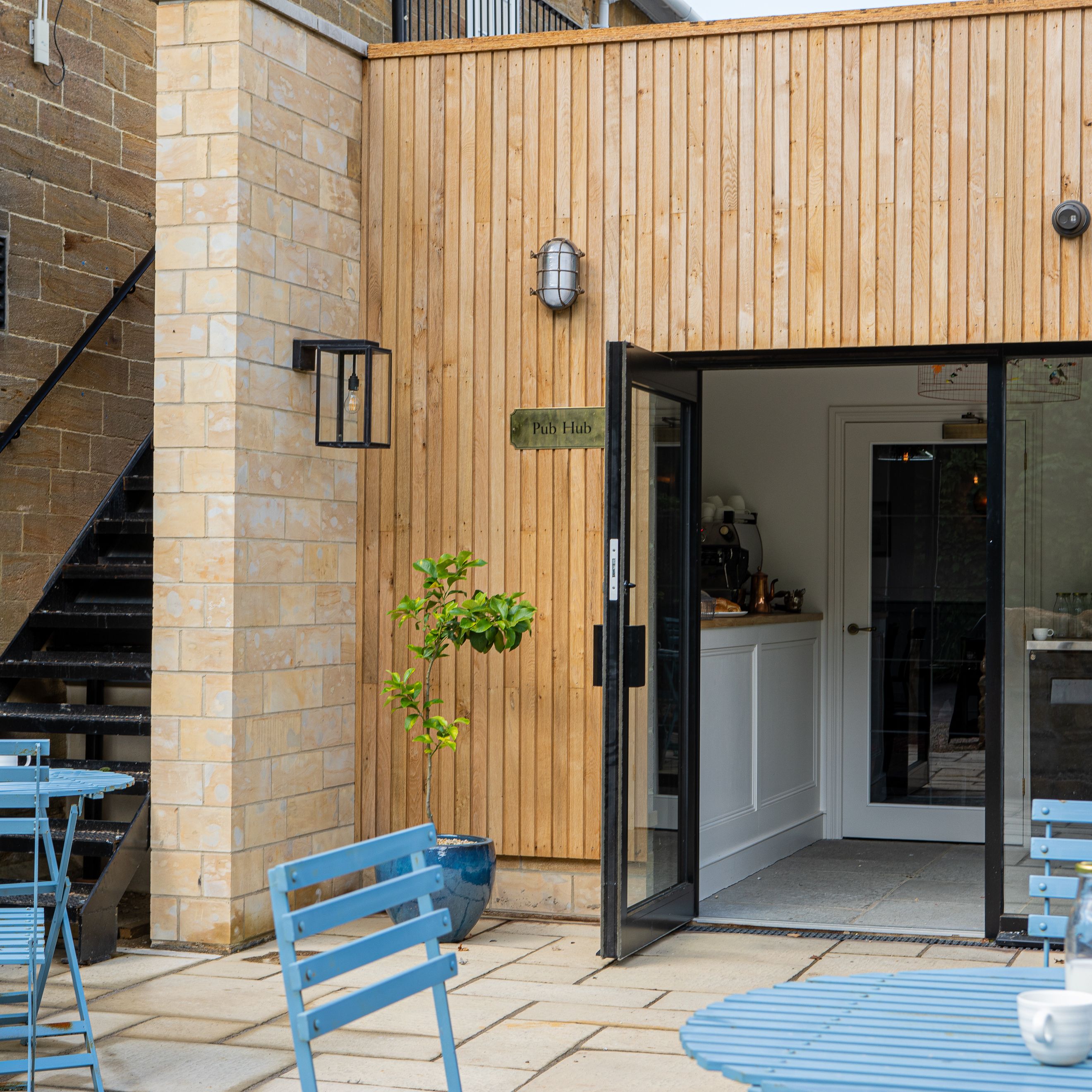 Outdoor seating area with blue tables and chairs in front of a building labeled 'Pub Hub'