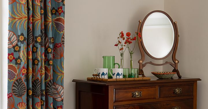 Wooden dresser with mirror and floral curtain in a bedroom