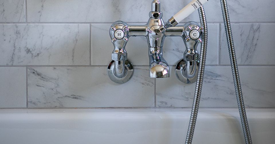 Close-up of a vintage-style bathtub faucet with shower head attachment