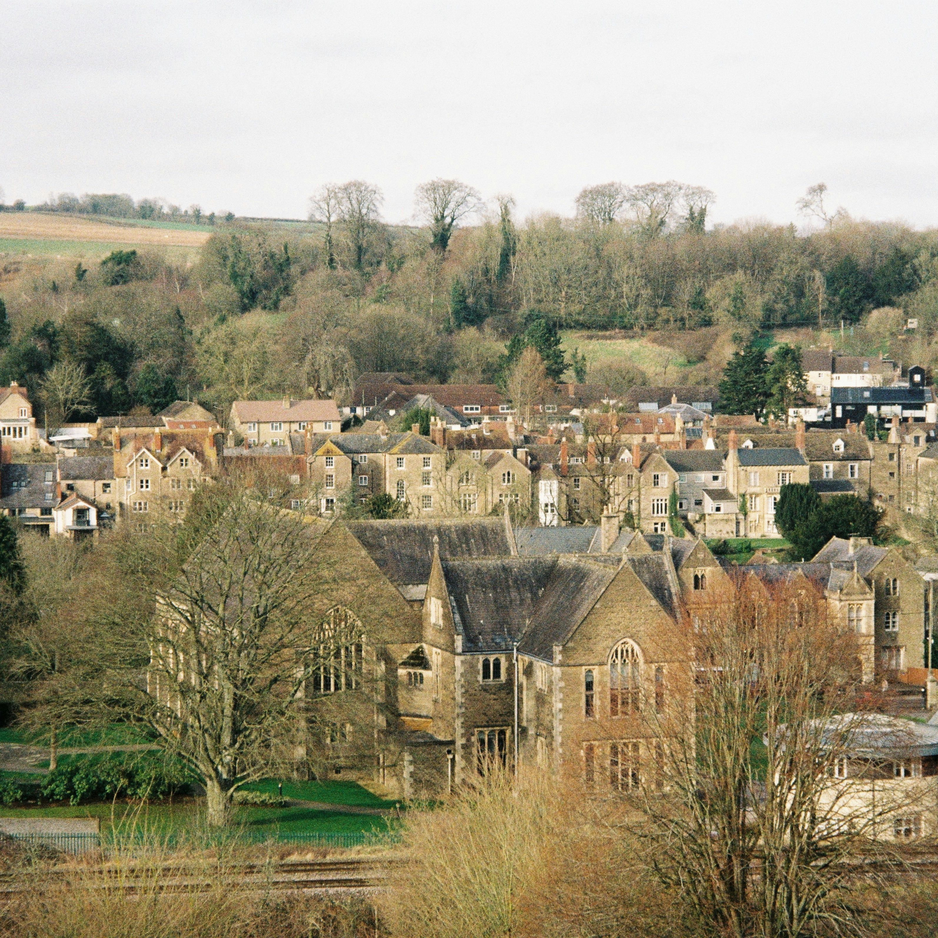 A picturesque English village with stone houses surrounded by fields and trees
