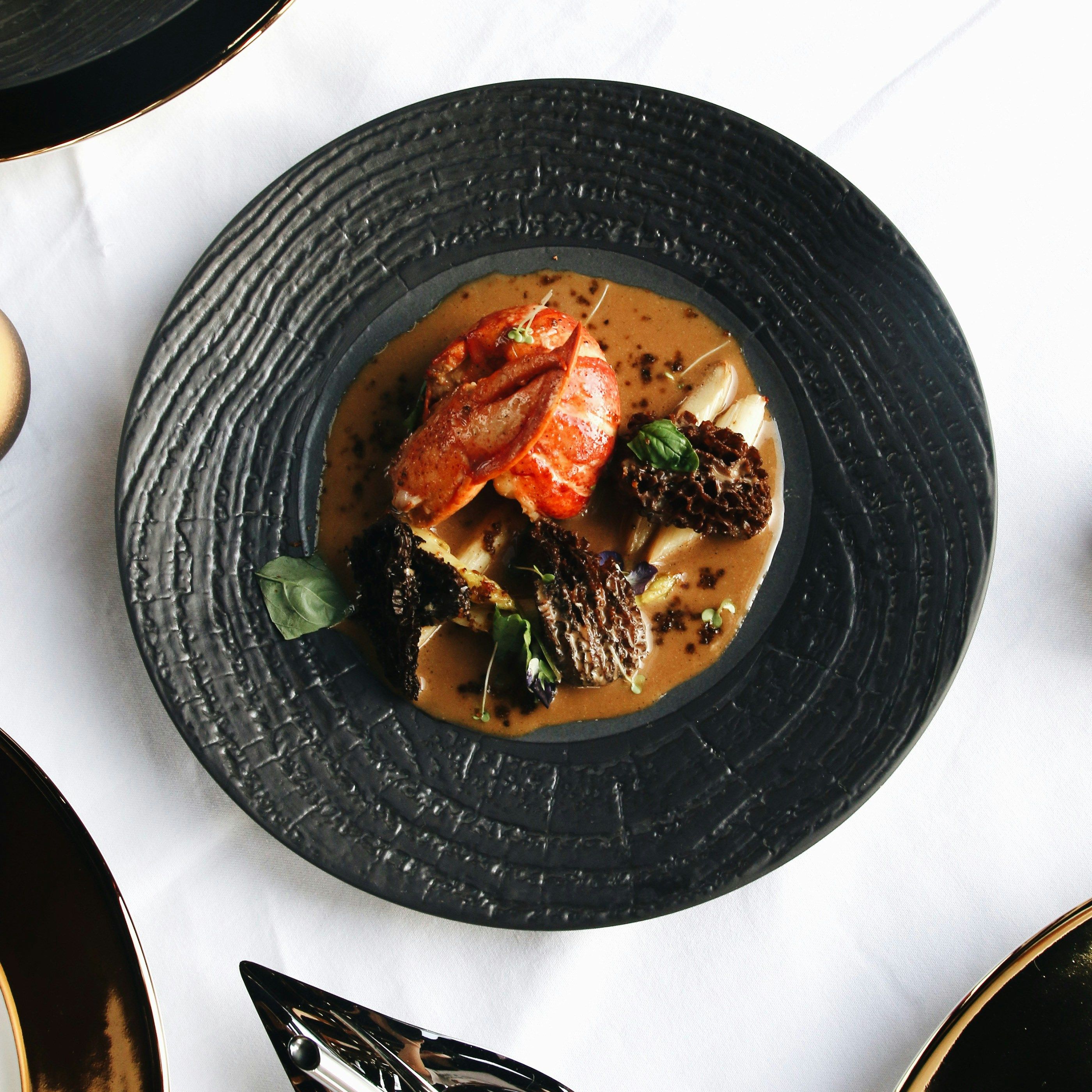 Gourmet seafood dish with lobster and mushrooms on a black plate