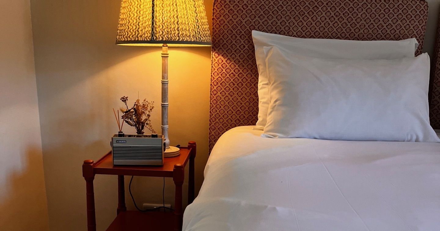 Cozy bedroom setting with lit lamp, bedside table, and white bedding