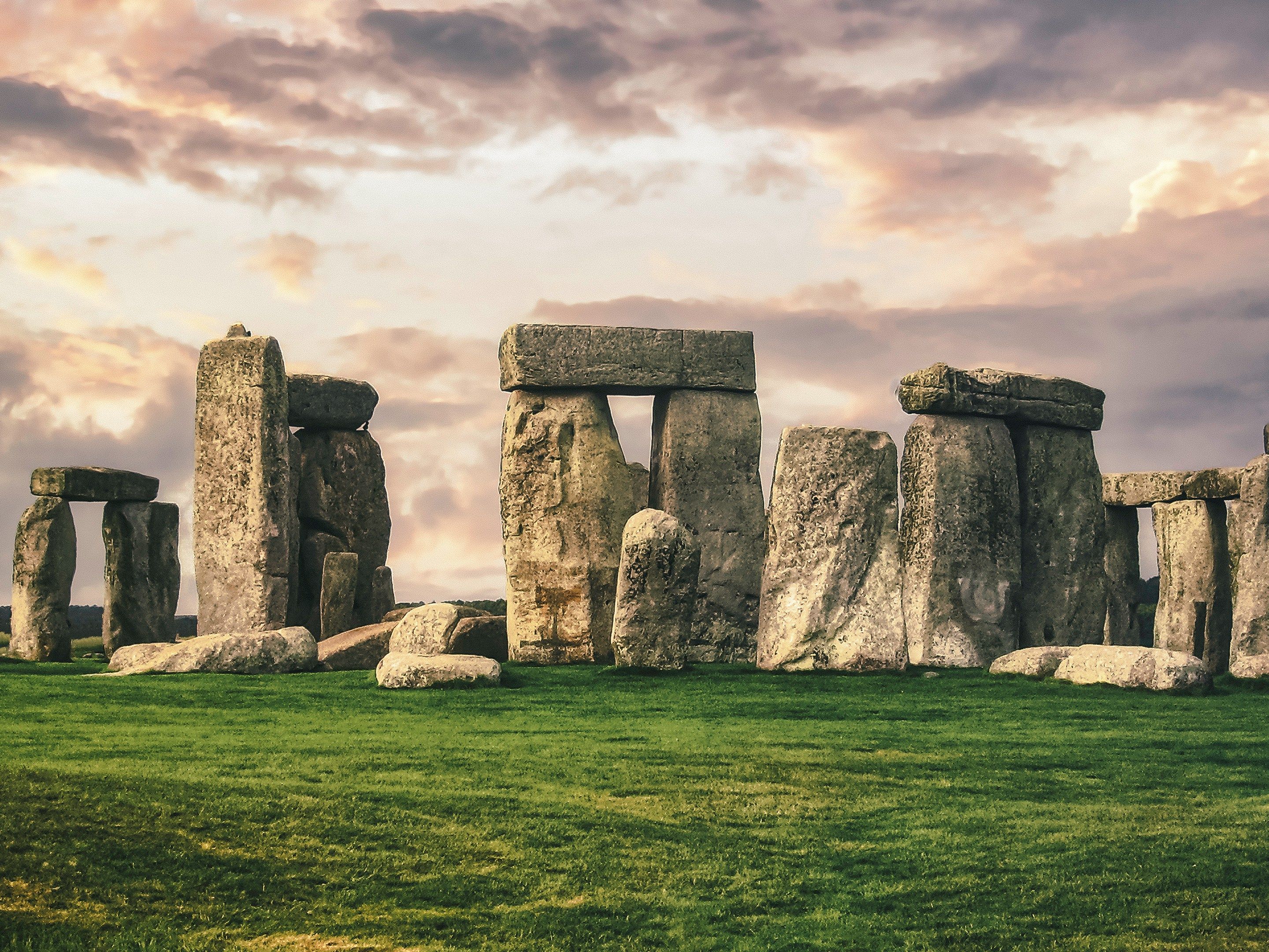 Stonehenge stone monument on a grassy field under a cloudy sky