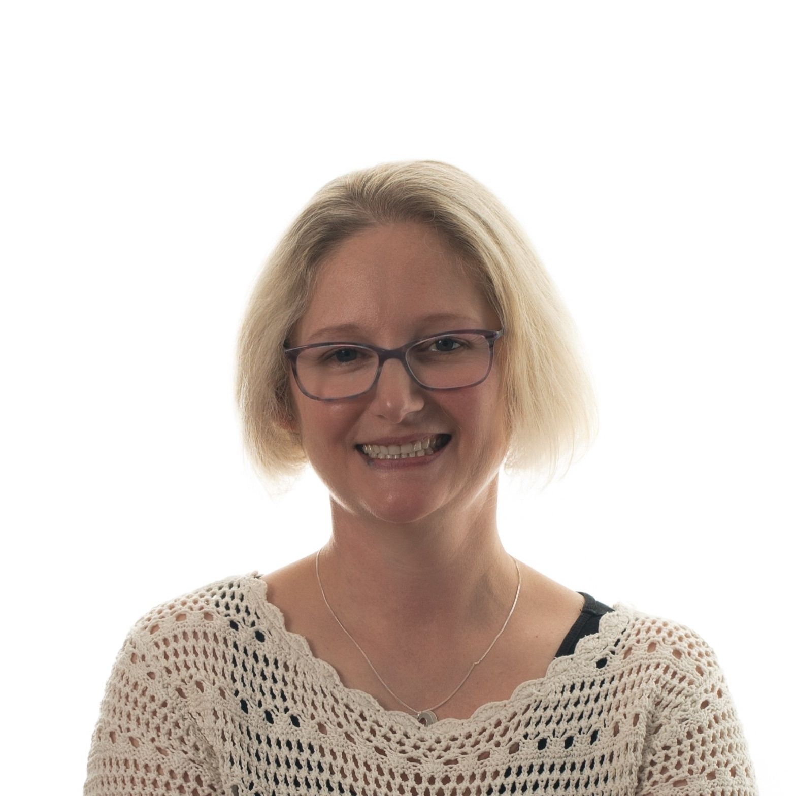 Smiling woman with short blonde hair wearing glasses and a crocheted top