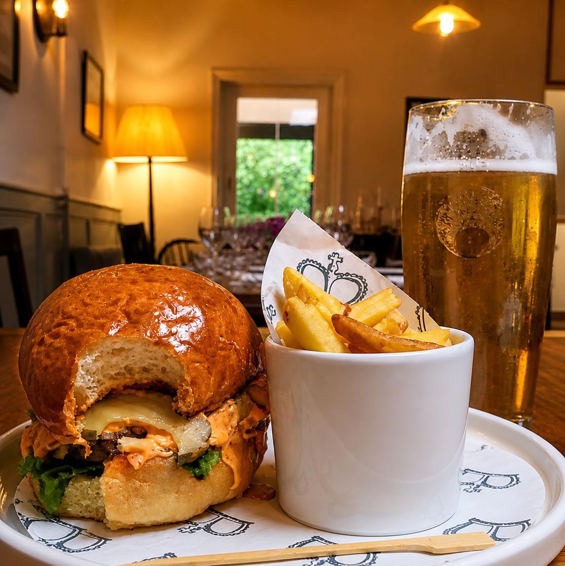 Burger with chips and a pint of lager on a plate in a warmly lit restaurant
