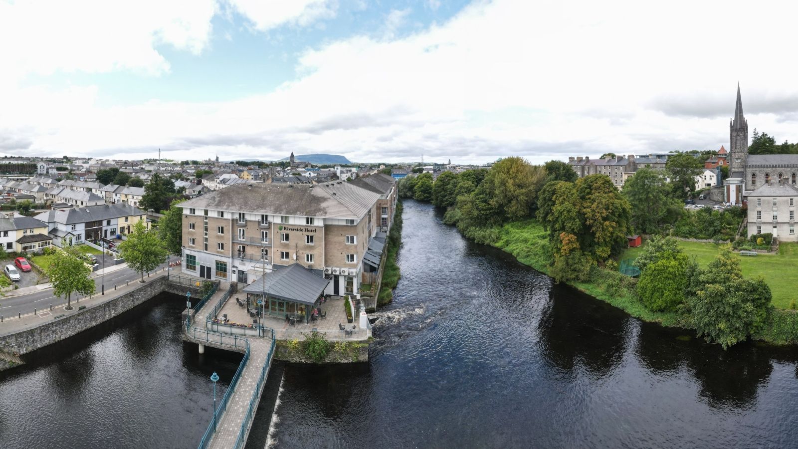 Aerial view of Riverside Hotel in Sligo, Ireland, adjacent to a flowing river and cityscape.