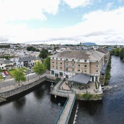 Aerial view of Riverside Hotel in Sligo, Ireland, adjacent to a flowing river and cityscape.