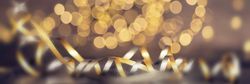 Blurred golden lights cover the background, whilst silver and gold chords adorn the front of the photo.