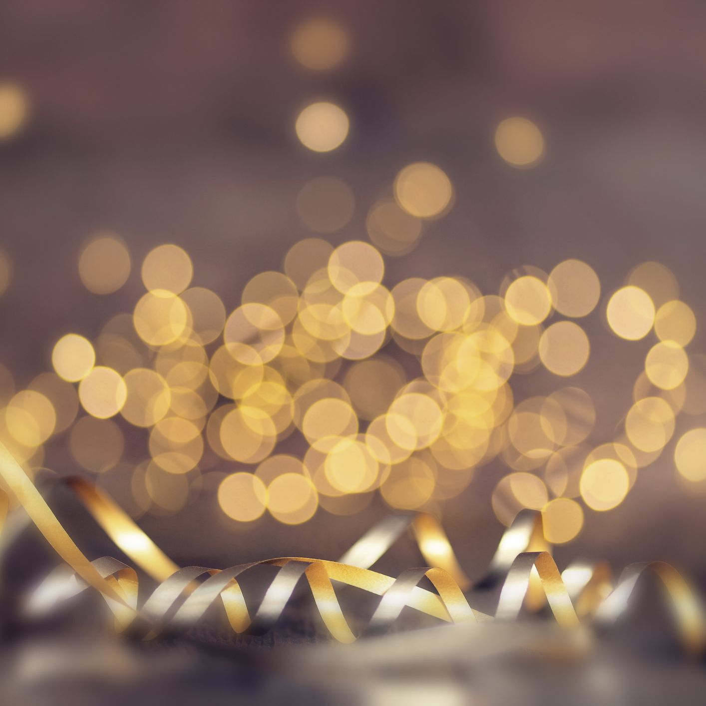 Blurred golden lights cover the background, whilst silver and gold chords adorn the front of the photo.