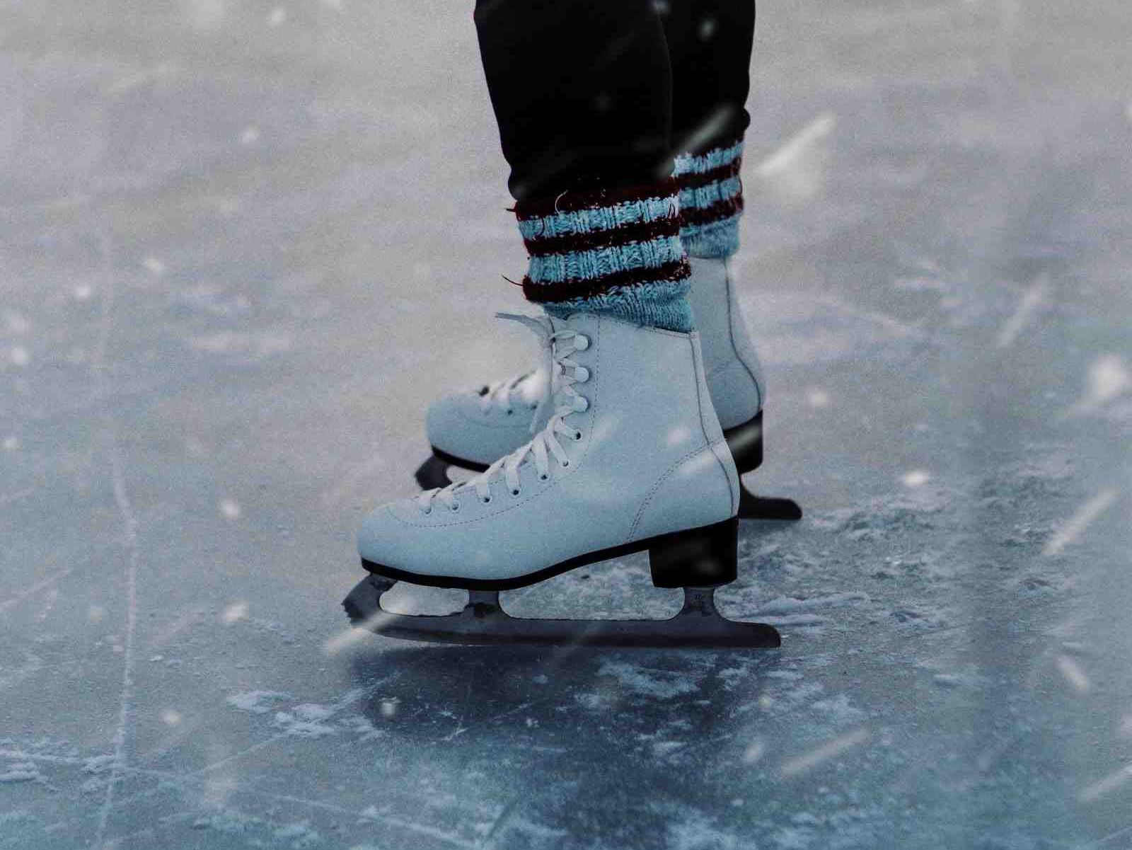 Close-up of a person wearing white ice skates on an ice rink