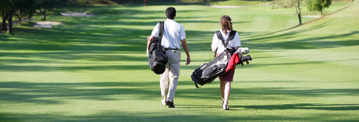 Two golfers walking along a fairway carrying their golf bags