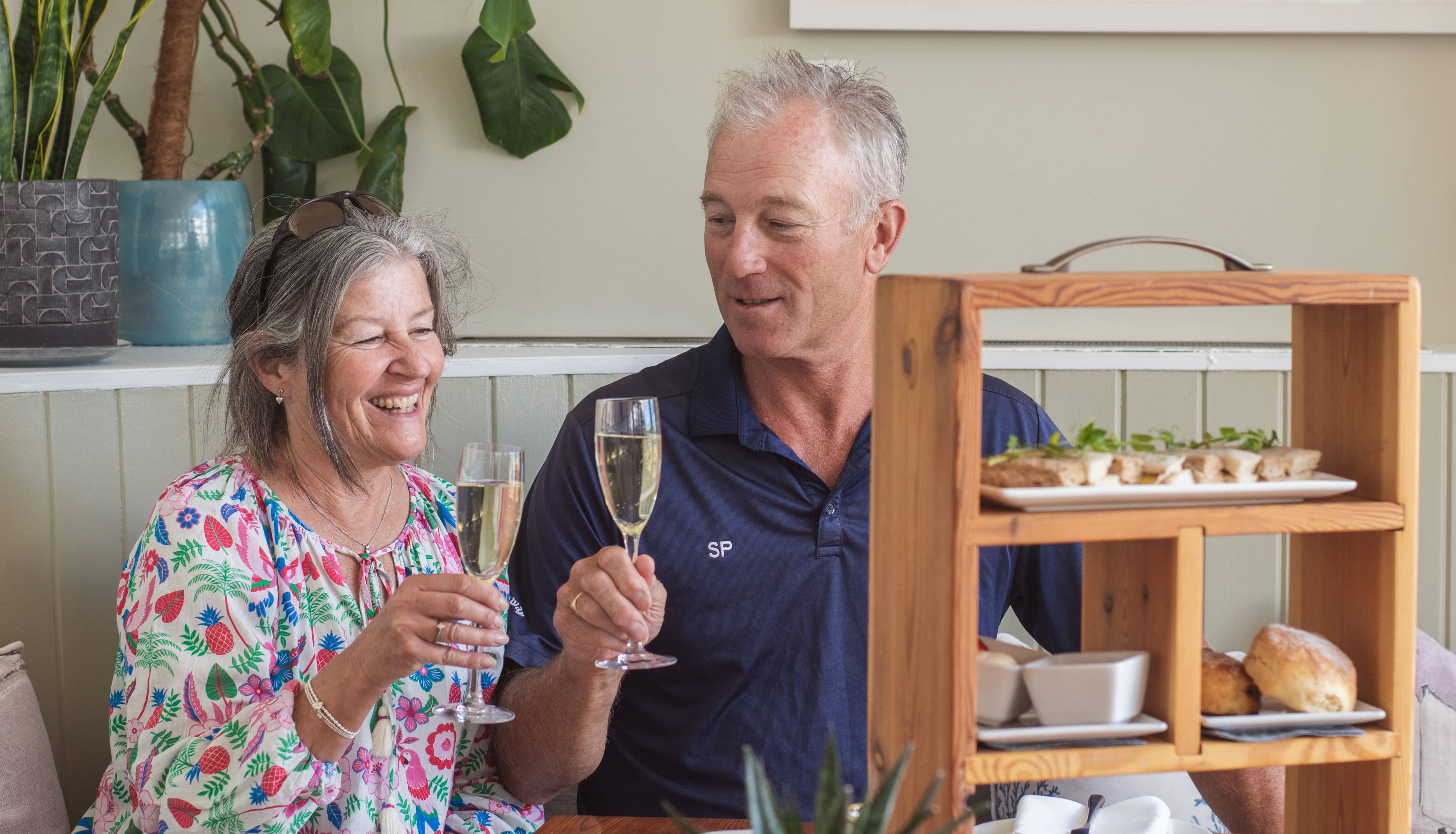 Older couple enjoying afternoon tea and toasting with champagne glasses.