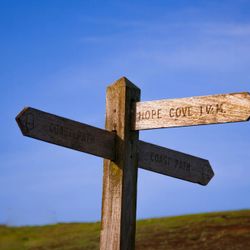 Wooden signpost pointing to Hope Cove and Coast Path against a blue sky
