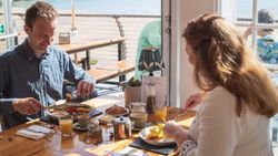 Two people enjoying breakfast at a sunlit restaurant table by the window.