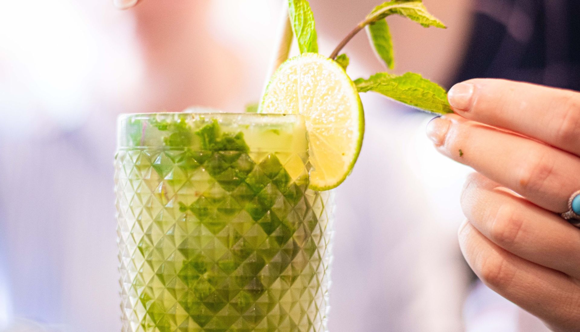Hand garnishing a refreshing mojito cocktail with mint and lime