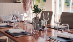 Elegant restaurant table setup with wine glasses, napkins, and a small potted plant centerpiece