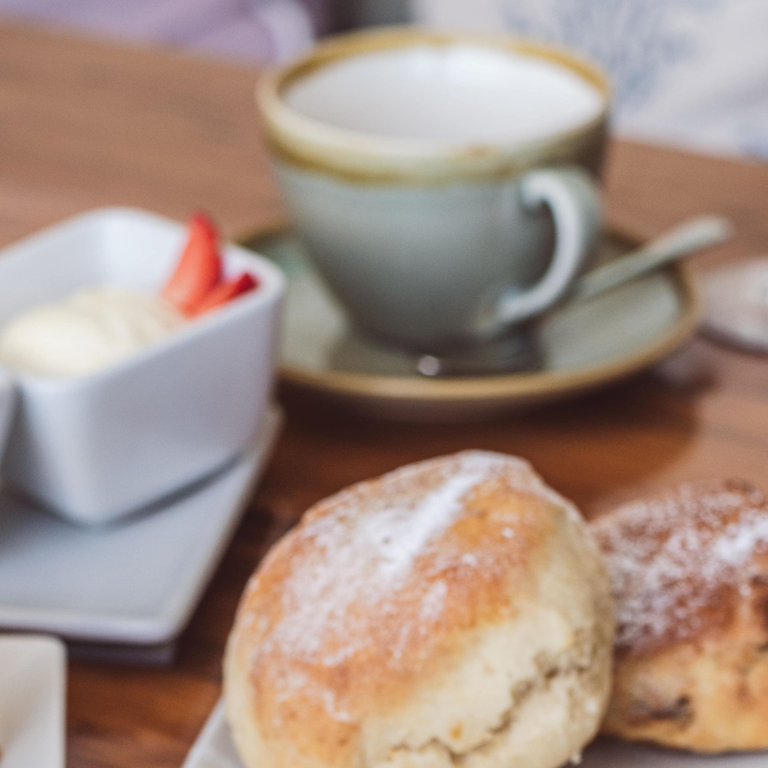 Afternoon tea with assorted finger sandwiches, scones with cream and jam, and cakes on a wooden table.