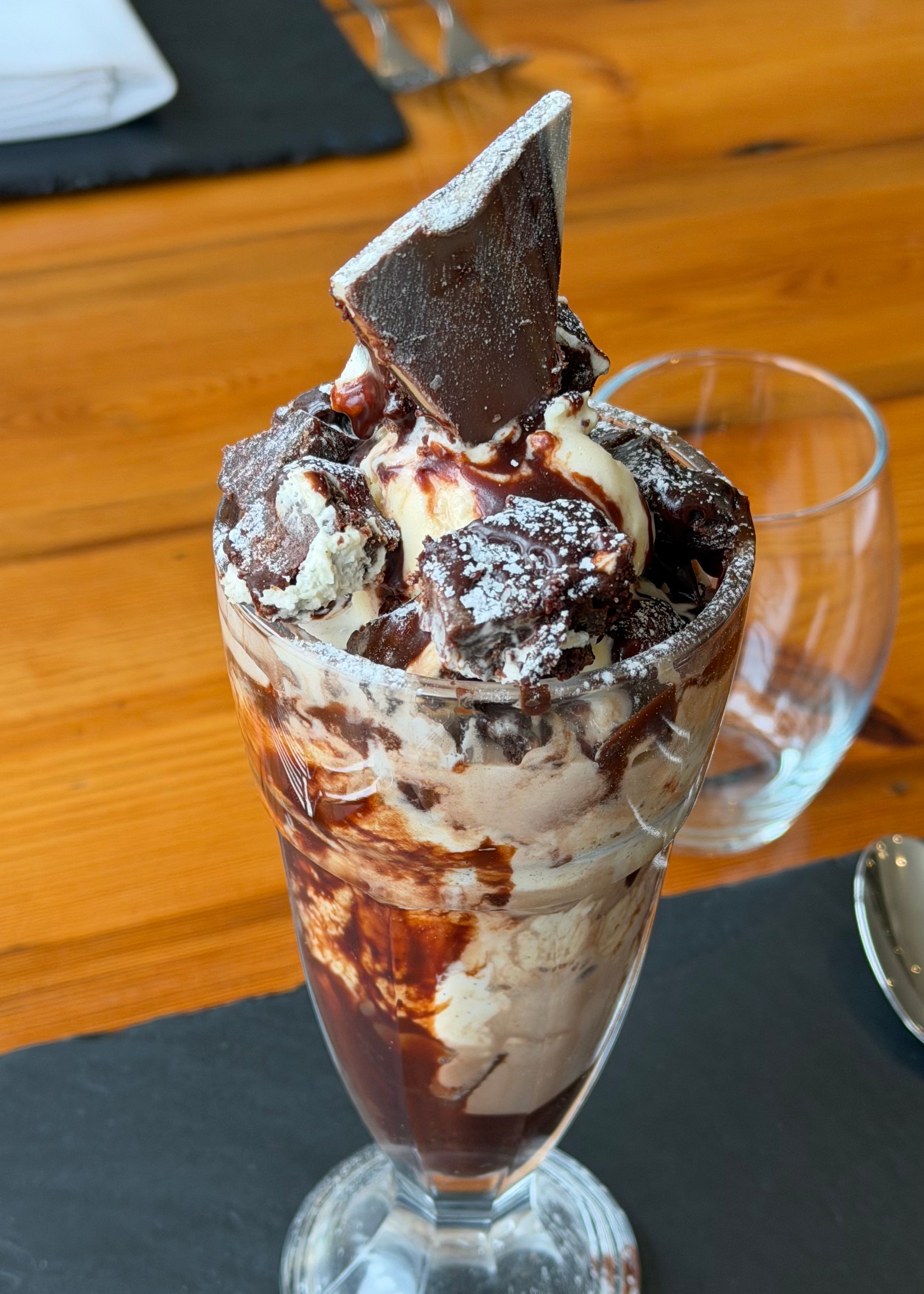 Chocolate brownie sundae topped with chocolate sauce and a chocolate shard in a glass