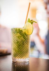 Mojito cocktail garnished with mint and lime in a textured glass