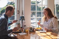 A man and a woman enjoying breakfast together at a bright, sunlit cafe table.