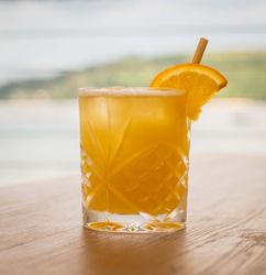 A refreshing orange cocktail garnished with an orange slice and a straw